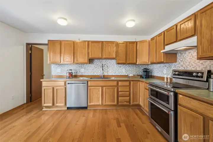 Kitchen features ample light-oak cabinetry & newer stainless steel appliances.