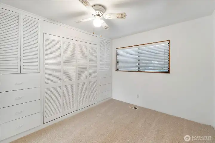 Bedroom featuring extensive built-in storage, including closets and drawers for efficient organization.