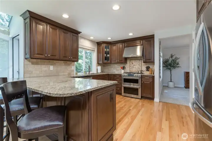 Gorgeous chef's kitchen features granite counters, tiled backsplash, and warm hardwood flooring.