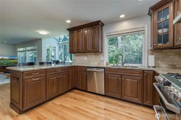 Well-appointed kitchen with warm wood finishes, stainless double oven and 5-burner gas range.
