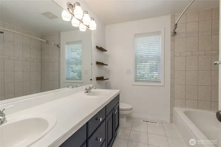 Full hall bathroom with double sinks, tiled shower surround