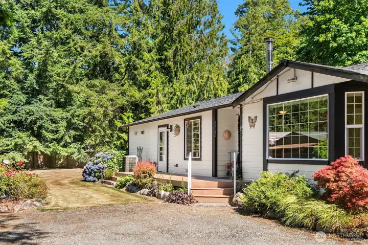 Sunny front porch enjoys views of the mature landscaping and beautiful flowers.