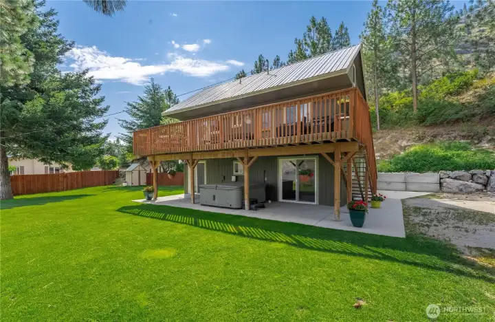 Exterior view of home w/ Upper Level lake view deck, private spa & grassy landscaped yard.