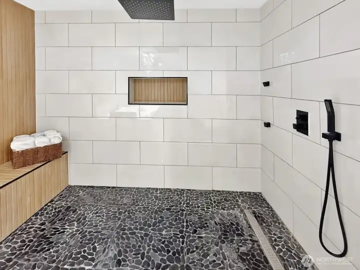 Enormous walk-in shower with waterfall shower head and built-in bench for a relaxing, spa-like experience