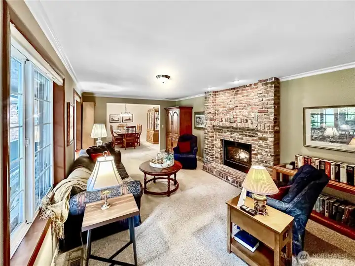 Front living room with gas burning fireplace with brick surround, crown molding, large, wood wrapped windows and easy access to the formal dining room.