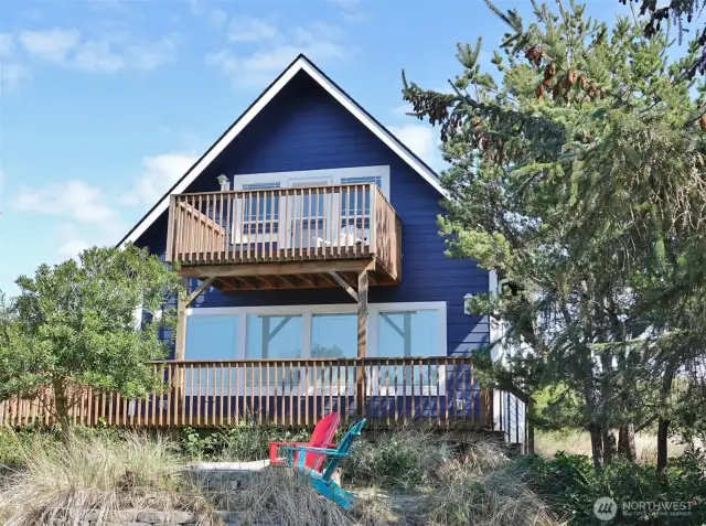 Rear view of this well-maintained Beach-style cottage surrounded by natural landscaping.