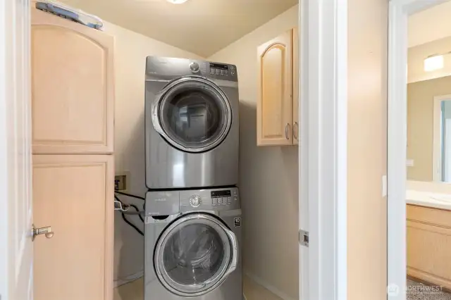 High-end newer SS stacking washer and dryer units anchor the laundry room, with large storage cabinet.