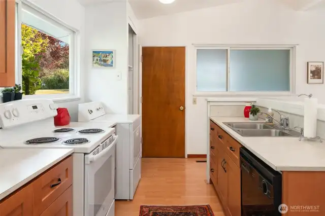 Galley kitchen with a view of the great room and the secret entry garden. Door to the "garage" is at the end. Opaque windows allow more light but block views of the utility space.