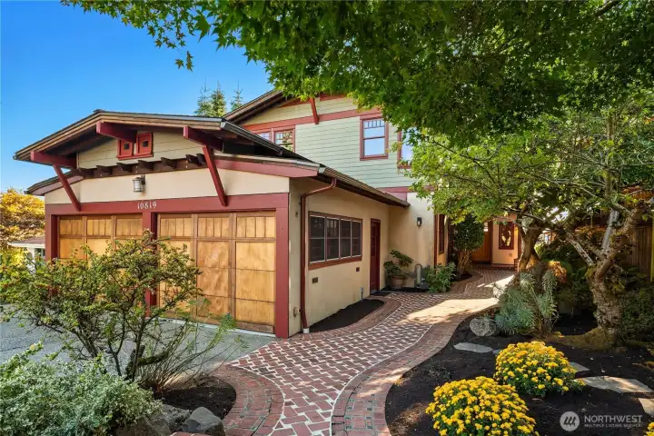 A charming brick pathway winds through lush landscaping to this Craftsman-inspired retreat, where thoughtful details create a welcoming first impression.