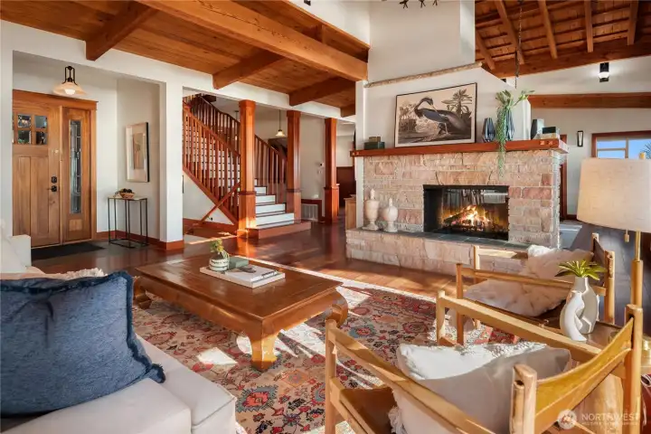 Wood beams, rich hardwood floors, and a double-sided stone fireplace anchor this inviting living space.