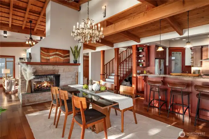 A sparkling chandelier and stone fireplace set the stage for elegant dining, seamlessly flowing into the open kitchen for effortless entertaining.