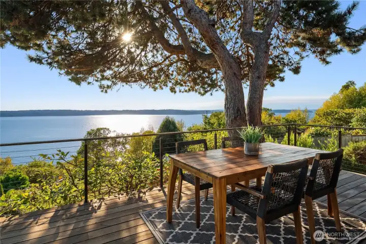 Dappled sunlight filters through evergreens onto this idyllic deck, where tranquil water views create the perfect backdrop for al fresco dining.