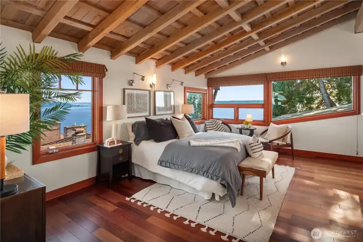With vaulted wood-beamed ceilings and panoramic windows, this primary suite offers an airy retreat framed by breathtaking water and mountain views.