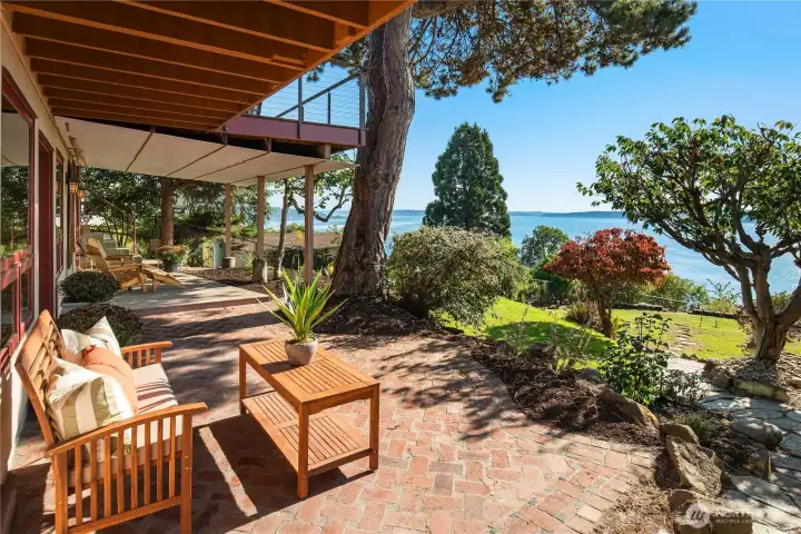 The lower patio offers a great relaxation area, with brick pathways, shaded seating, and sweeping views of Puget Sound - an ideal spot to kick back and enjoy the gardens and water beyond.