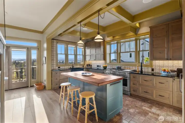 The vintage-inspired kitchen features knotty alder cabinetry, a walnut-topped island milled from a tree that once stood on the property, and beautiful beamed ceilings. Additional highlights include cabinet panel appliances, a professional-style 48" dual-fuel range and oven, and a spacious walk-in pantry.