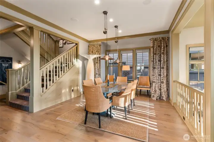 The spacious dining room opens seamlessly to the sunken living area on the right, creating an inviting and connected flow throughout the main level. An extra-wide staircase provides access both downward to the studio on the lower level and upward to the three en-suite bedrooms above. The home was thoughtfully designed with future flexibility in mind and is already framed for a three-stop elevator, with three generous storage closets currently occupying the space designated for potential installation.