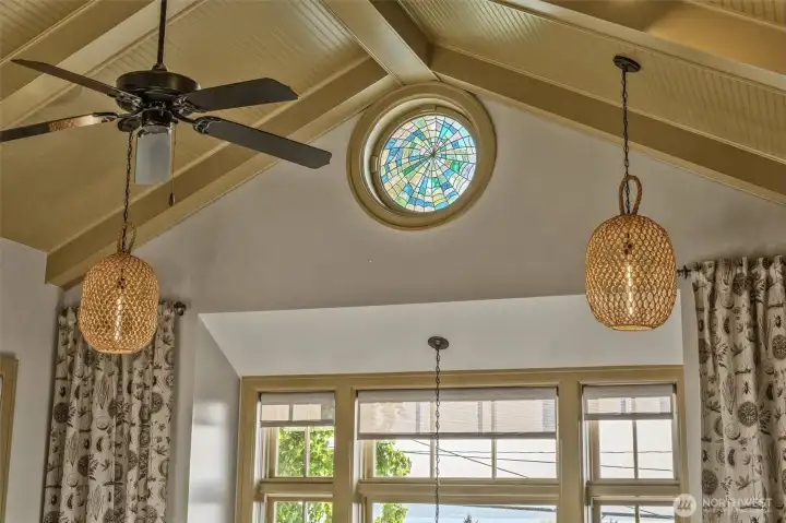 Another of the home’s custom stained-glass windows creates a striking focal point in the vaulted living room, casting colorful light and adding a sense of artistry and craftsmanship to the space. This unique detail enhances the room’s soaring architecture while bringing warmth, character, and another truly one-of-a-kind design element to the home.
