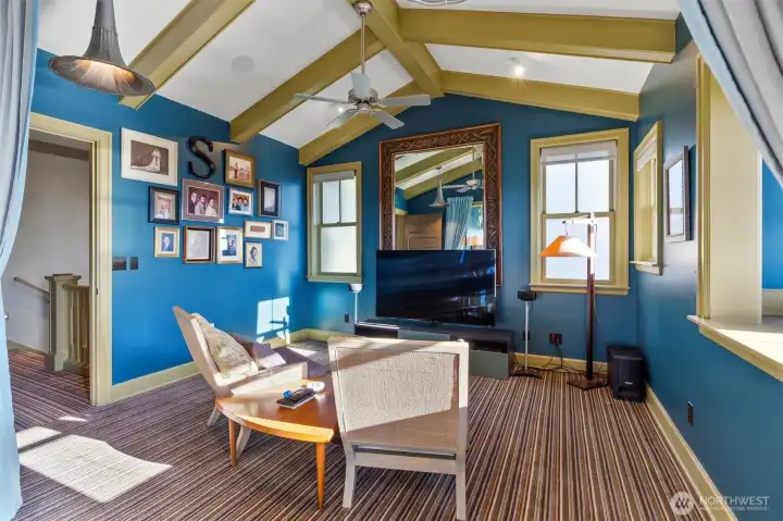 The primary suite showcases beautiful beamed and vaulted ceilings that enhance its sense of space and character. A charming sitting area provides the perfect nook for curling up with a book or enjoying a relaxing movie in a private, comfortable setting.