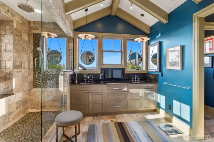 The primary bathroom is beautifully finished with travertine throughout, creating a warm, spa-like atmosphere. It features dual vanities for added convenience, along with a luxurious walk-in shower that offers tranquil views, turning everyday routines into a calming, restorative experience.