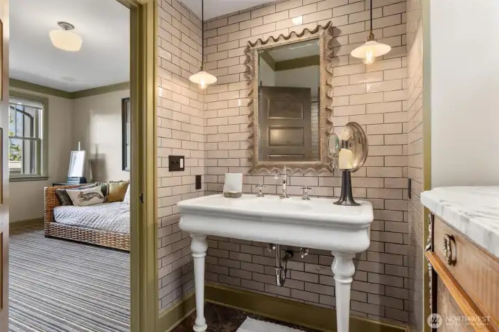 Charm overload! This full en-suite bathroom features a beautifully preserved antique sink and a striking tiled wall, blending timeless character with thoughtful design details.
