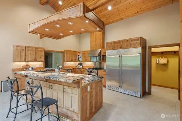 There is an eating bar for at least four seats and a double refrigerator/freezer. The gas range has a commercial hood and there is a second oven in the island. The laundry room is just beyond the kitchen.