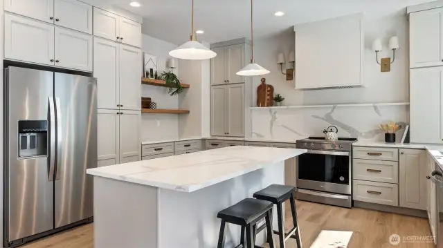 Kitchen has a massive amount of cabinets and quartz counters and backsplash.