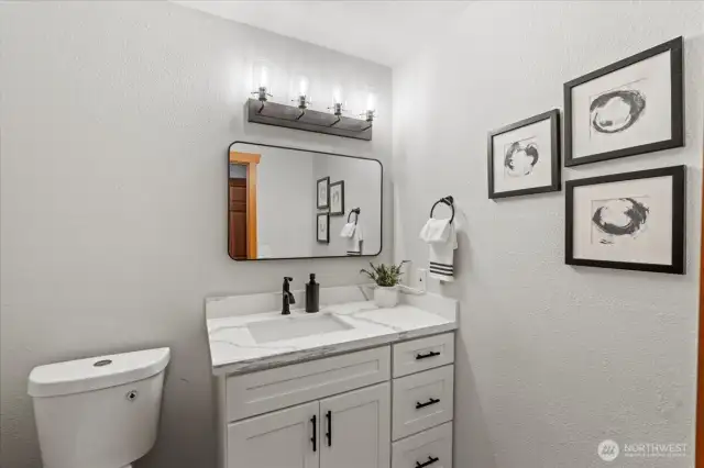 The main floor guest bathroom is newly remodeled and features new cabinets, quartz counters, mirror, lighting and toilet.
