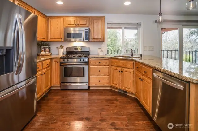 The thoughtfully designed kitchen includes pantry space, warm cabinetry, granite counters, and stainless steel appliances.