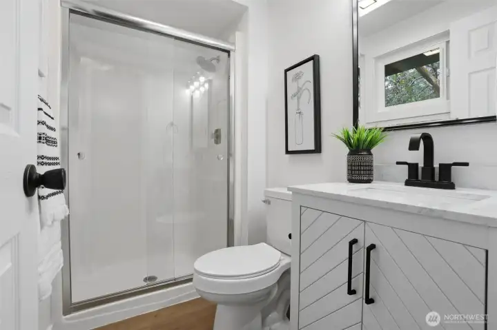 Primary bedroom ensuite with new flooring, toilet, vanity, mirror and lighting