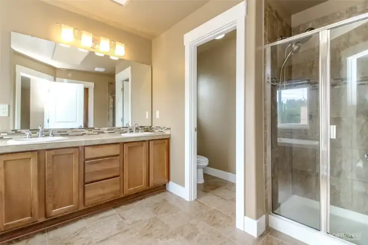 Beautiful tile work, dual sinks, and a large glass-enclosed shower.