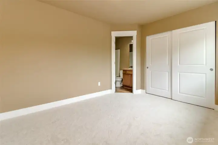Comfortable bedroom featuring plush carpeting, generous closet space, and direct access to a private en-suite bathroom.