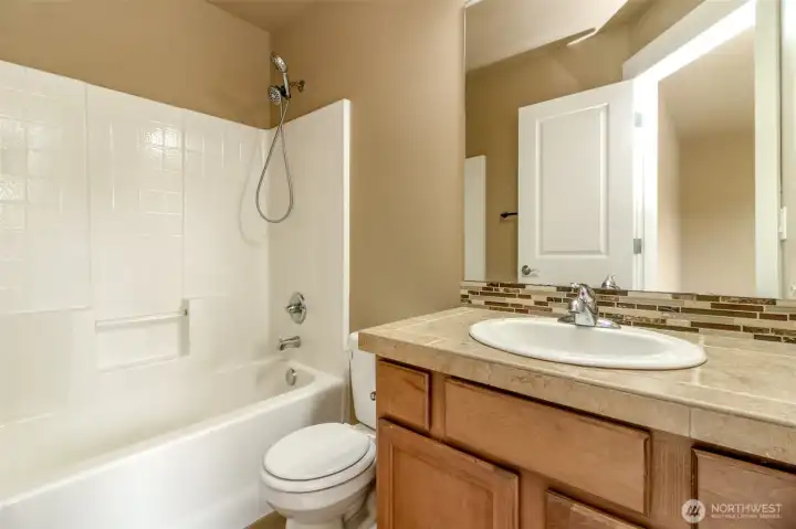 Full bathroom with tiled vanity, durable finishes, and tub/shower combination designed for everyday convenience.