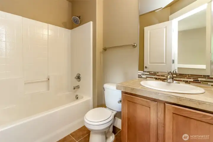 Clean and stylish bathroom with attractive tile work, quality cabinetry, and a full tub/shower combination.