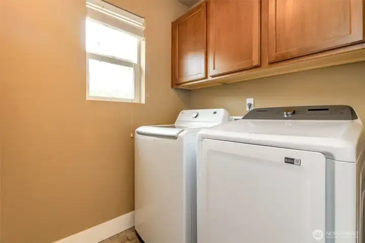 Convenient laundry area with storage cabinetry and full-size washer and dryer included.