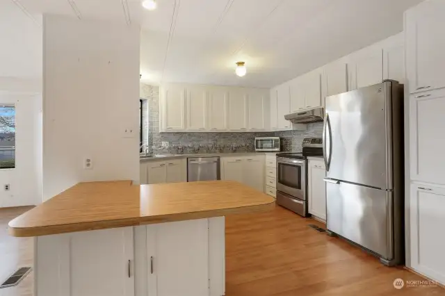 Updated kitchen with laminate flooring, refaced cabinets, stainless appliances and an eating bar.