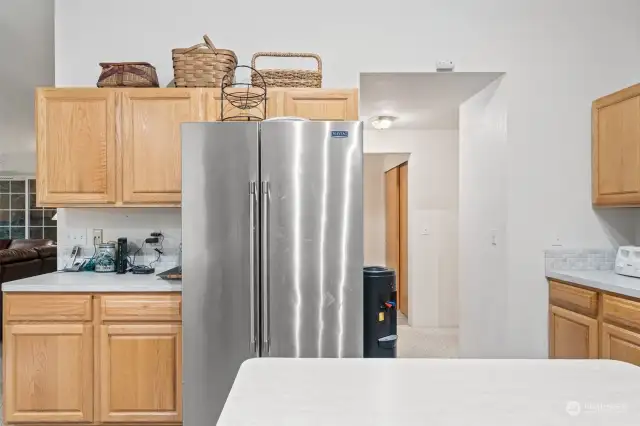 Kitchen with doorway to entry on right.  Large pantry on left of doorway behind refrigerator.