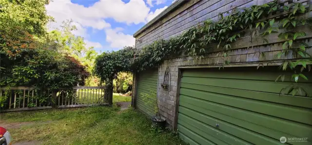 Rustic charm meets coastal utility in this two-car garage, where classic green doors, vine-draped shingles, and handcrafted accents blend beautifully into the lush Nahcotta landscape. Whether you’re storing kayaks, tackling DIY projects, or simply pulling in after a day at the bay, this garage is equal parts practical and picturesque.