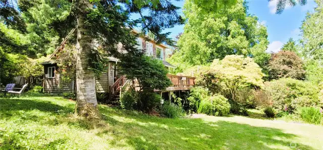 Surrounded by vibrant greenery and mature trees, this shingled retreat offers a spacious deck for entertaining or quiet moments in nature. With sun-dappled views and forested charm, it’s Nahcotta serenity at its best.