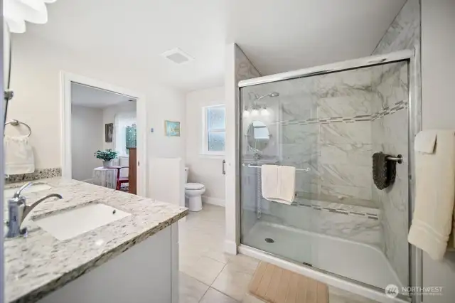 Shared bath area with a big shower and porcelain tile surround.