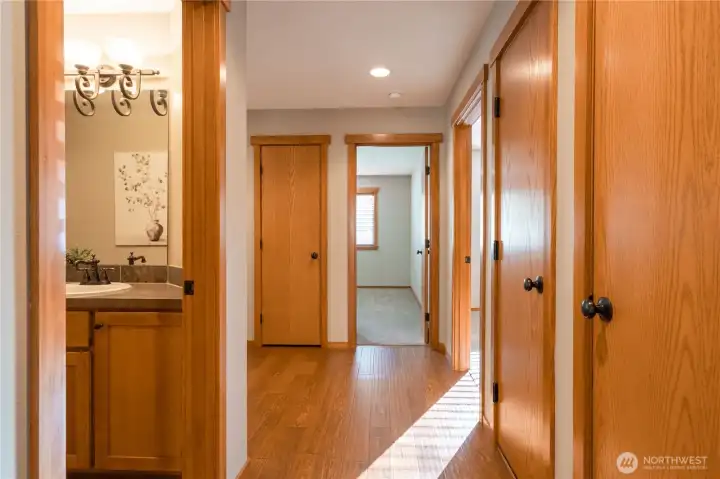 This view is standing at the entry to the living room and looking back to the front entry. The first door on the right is a pantry, second door is the furnace area.  The door on the left is the guest bathroom.  The open door straight ahead is the second bedroom.  The open door on the right is the primary bedroom.