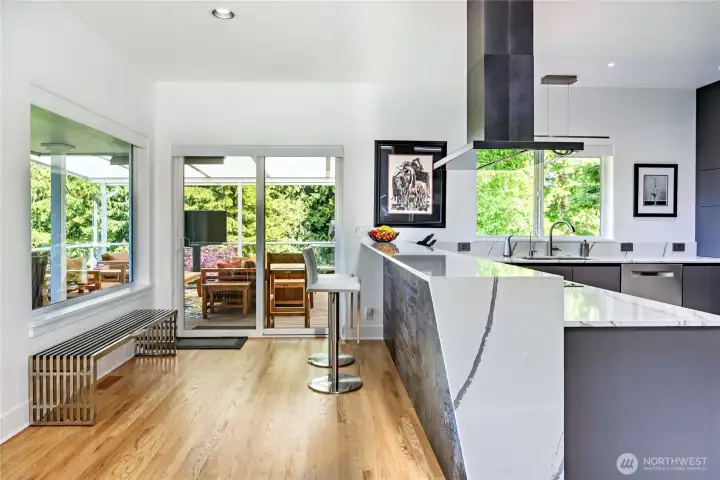The eat-in kitchen area features a Dekton fascia, which is a carbon neutral ultracompact porcelain surface; hardwood floors: Silestone Et. Bella counter-tops; and walls of windows to bring in the views and natural light.