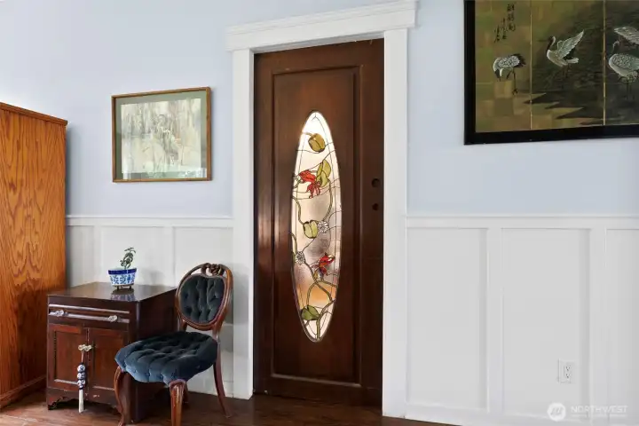 This is a solid wood pocket door featuring the owners custom stained glass leading into the parlor off the kitchen.