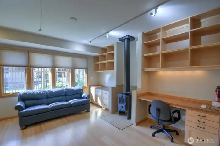 Sharp shelving & desk flank a wood stove that works to heat whole place when used.