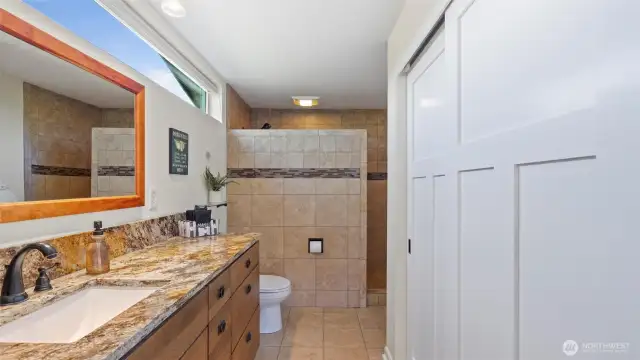 Primary bath has large walk-in shower, closet and heated floors! Note the natural light shining through the transom window.