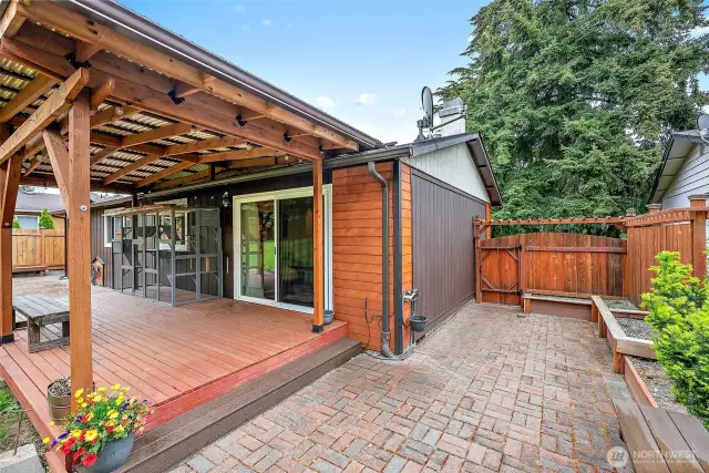 Backyard entertaining made easy with a paver patio, raised garden beds, and gated access to the side yard.