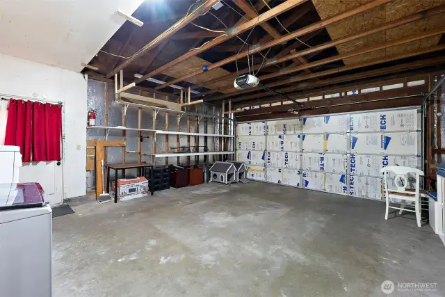 Spacious two-car garage with exposed beams, built-in shelving, and insulated doors—ideal for storage or workshop use.