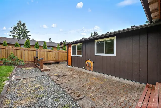 Fully fenced backyard with gravel and paver pathways, custom hose storage, and raised planting beds.