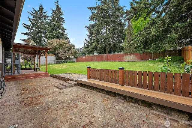 A spacious backyard framed by mature trees, creating privacy and a lush natural setting—ideal for play or gardening.
