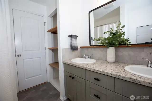 Hall full bath has double vanity, tiled tub surround, and awesome storage tucked behind the door!