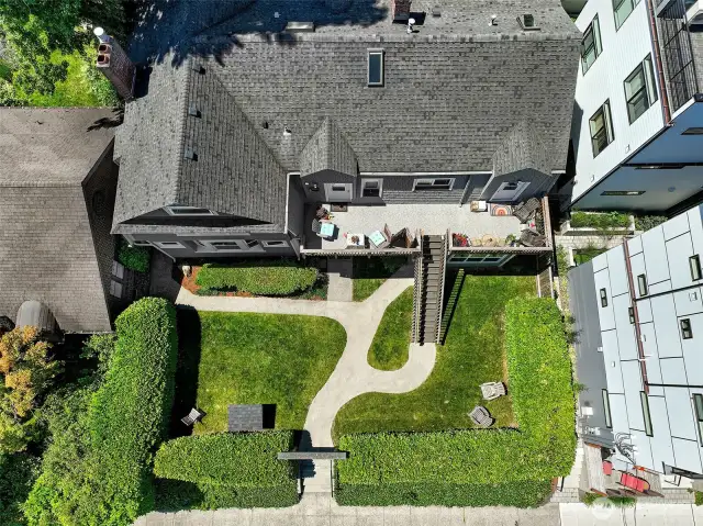 This overhead view of Laurel Gate reveals a rare combination in Capitol Hill multifamily: a flat, 7,200 SF street-to-alley parcel with mature landscaping, formal walkways, and seven dedicated off-street parking spaces tucked discreetly in back. The colonial revival building—surrounded by a privacy hedge—sits within LR3(M) zoning, offering income today and the possibility of added density tomorrow. A quintessential Capitol Hill garden courtyard, rooted in Seattle history.
